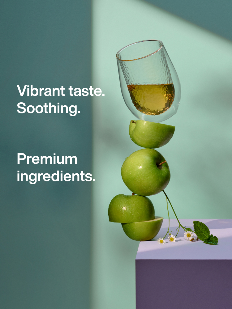 Stack of apples balancing with a cup of tea on top