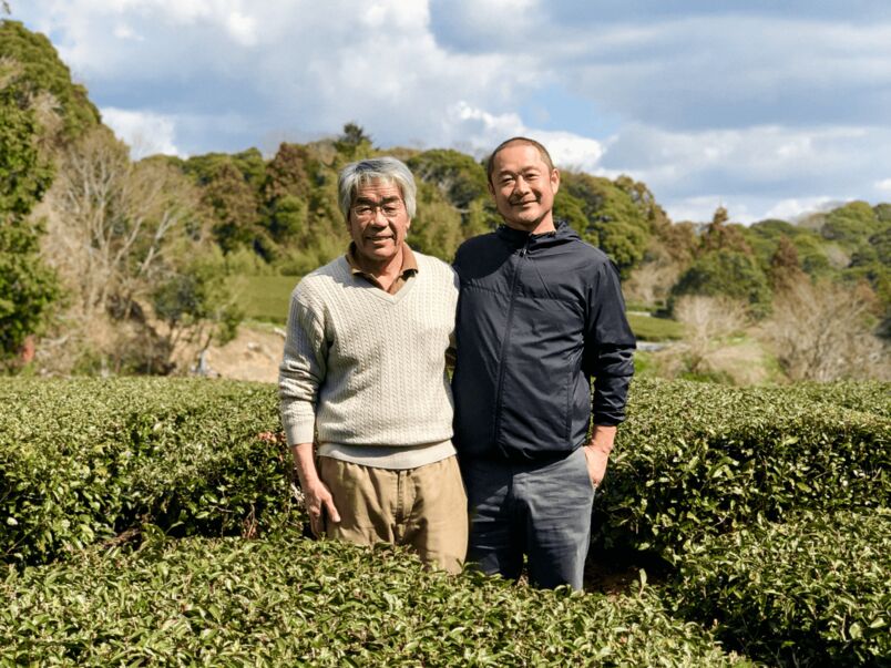 Father and Son  standing side by side in a tea field
