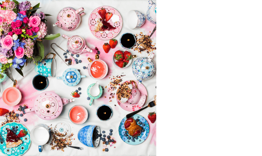 Colourful teapots with flowers and tea arranged sporadically on a table top
