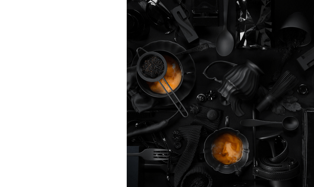 Lots of black tea pots and tea cups on a table