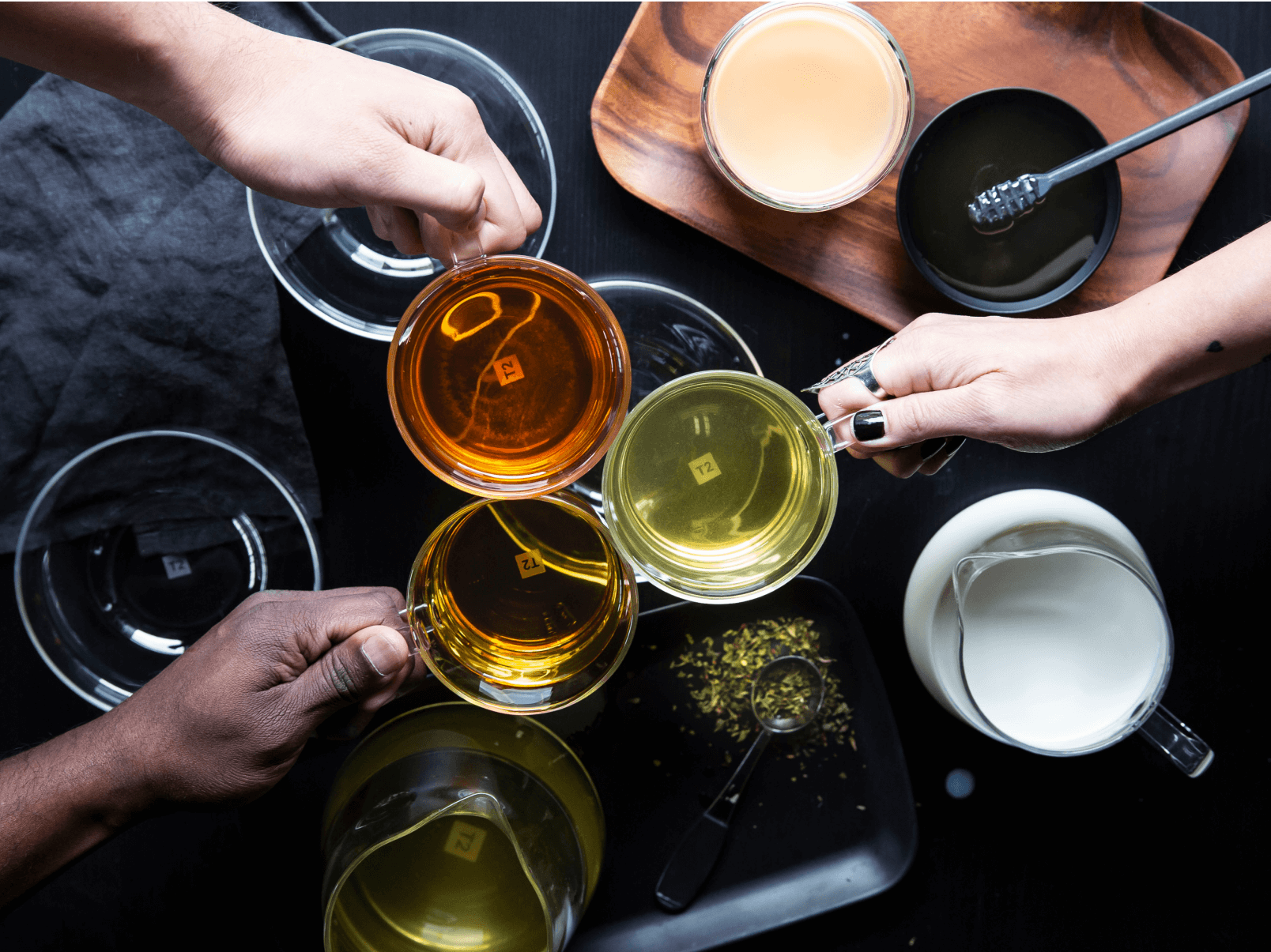 Three hands hold tea cups