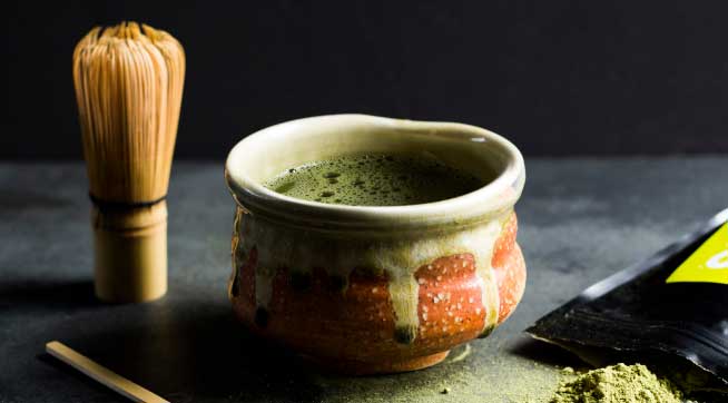 A cup of T2 Matcha tea and a matcha whisk