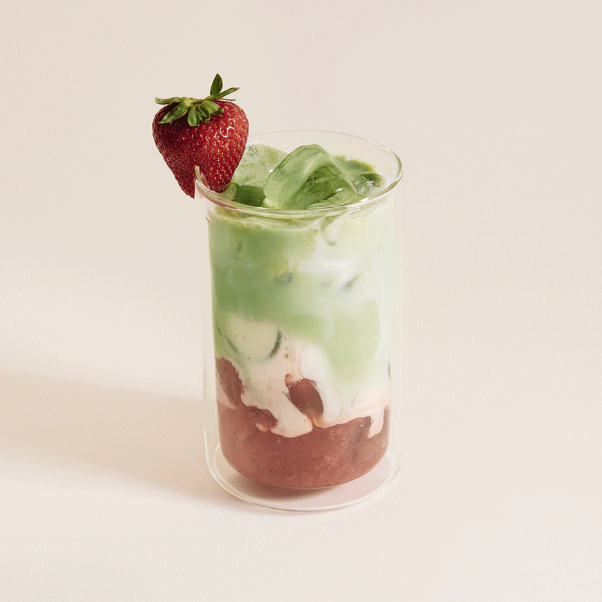 Strawberry and blueberry matcha lattes surrounded with fresh strawberries and blueberries