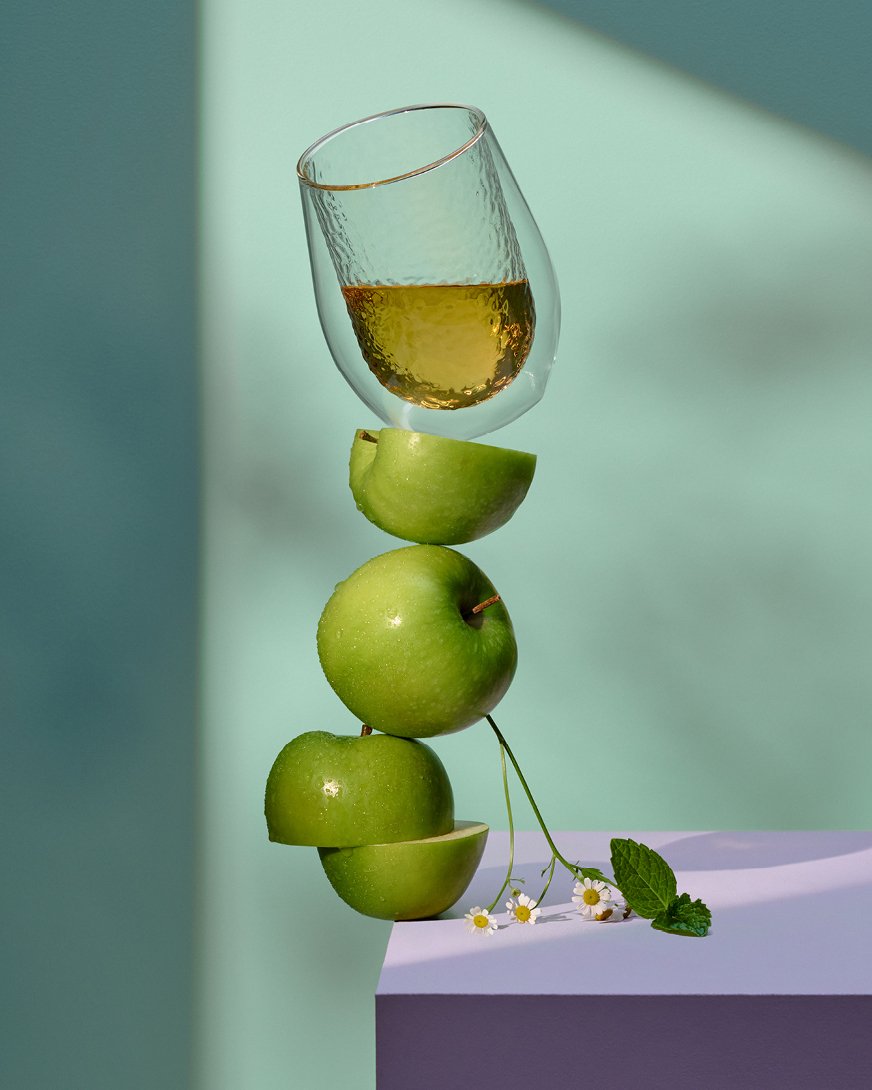 Tea in a glass balancing on top of stacked apples