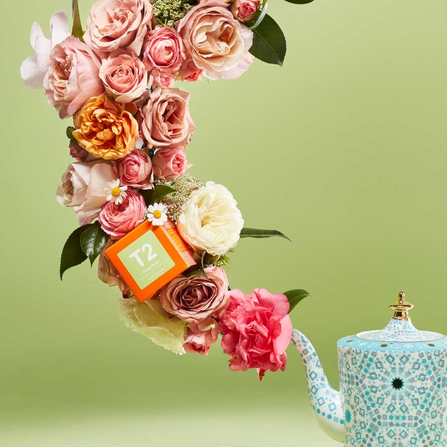 A bouquet of roses with a box of T2 Green Rose Tea inside